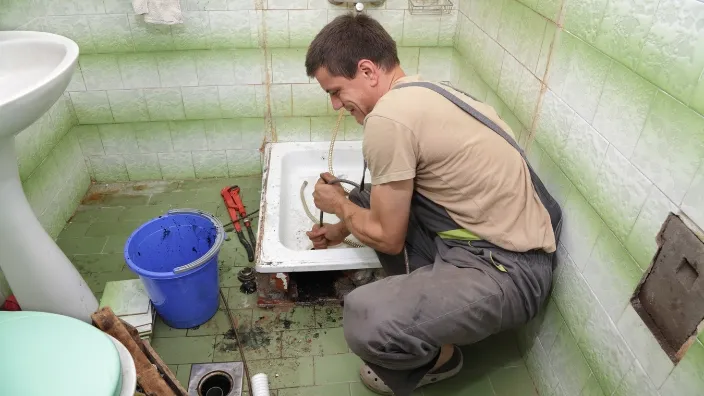 professional plumber doing sth to open the shower drain