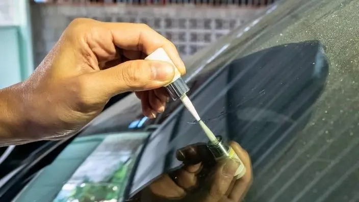 applying superglue on cracked windshield of a car